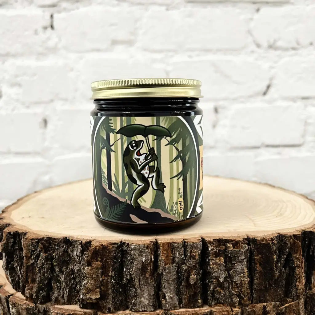 Tattoo-art label candle with frog holding a leaf, inspired by the Hall of Mosses trail in the Pacific Northwest, by Gold Dust Collective.